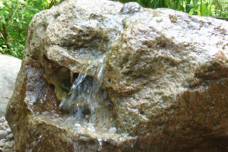 aus einem Quellstein sprudelt Wasser hervor
